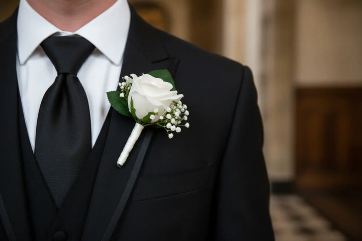 White rose boutonniere on a light gray background