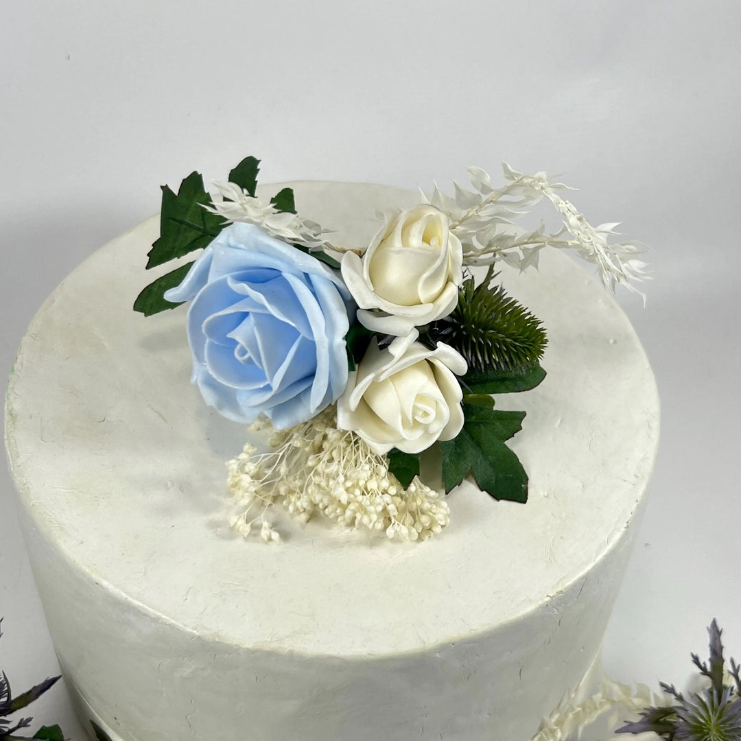 White cake with blue and white roses on a light gray background